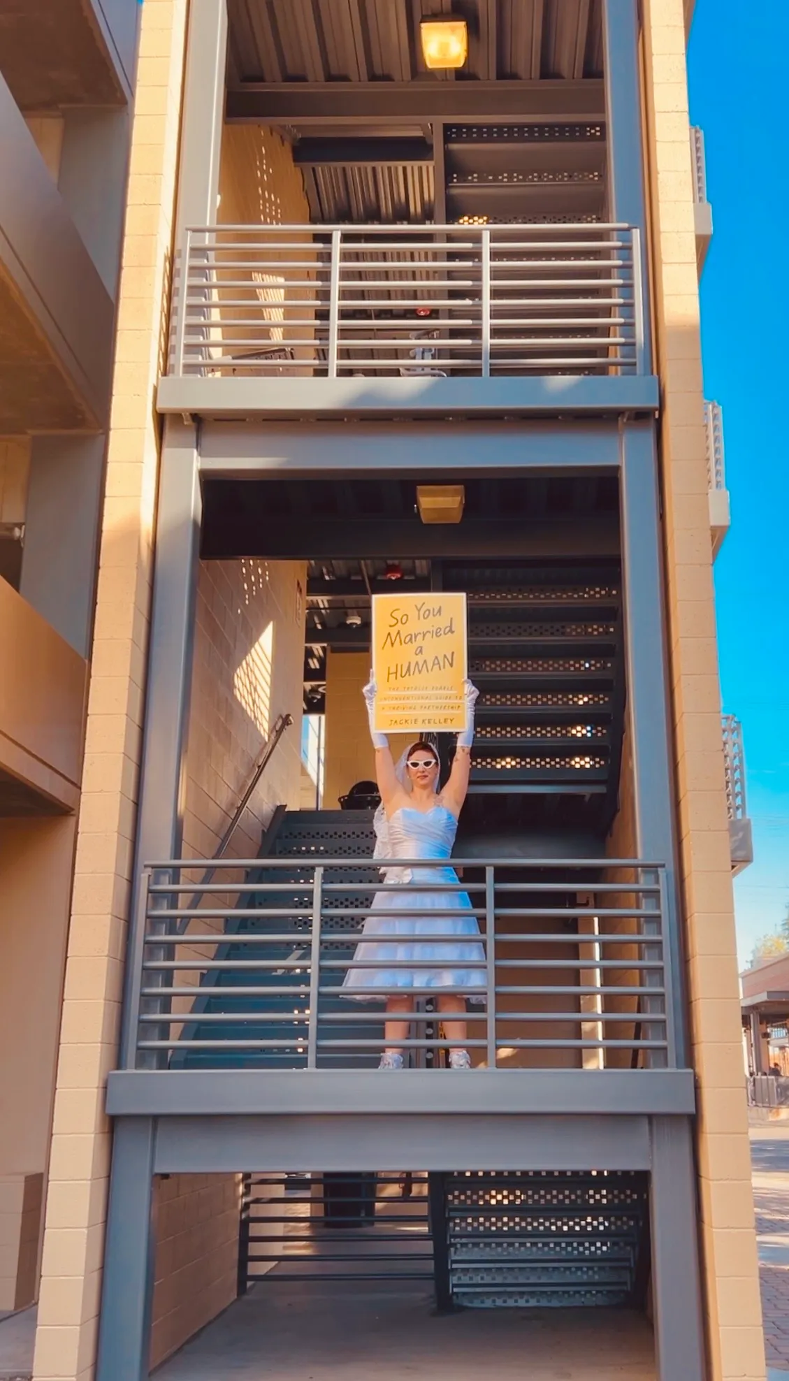 Jackie Kelley holding the four-foot printed cover above her head at the top of a staircase.